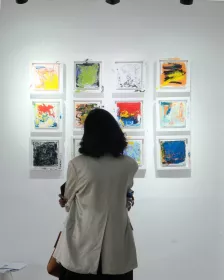 Eine Frau im Ausstellungsraum, die auf der Wand einzelne Kunstwerke betrachtet